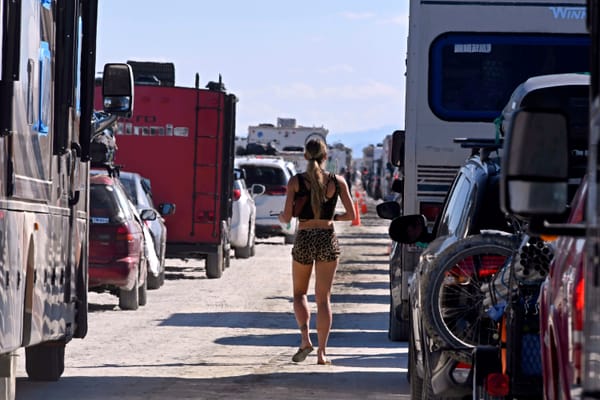 A woman walks between cars exiting the Burning Man festival in Black Rock City.