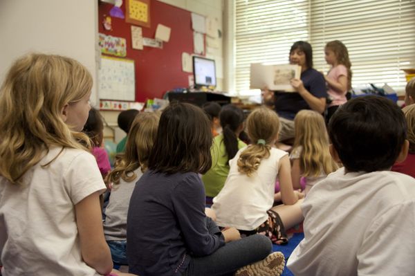 a teacher reads to children in a school classroom